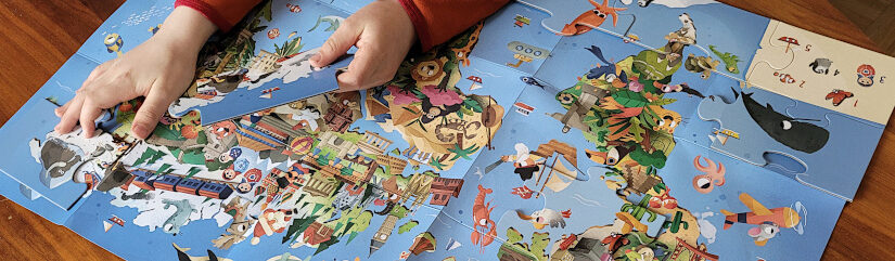 Kinderhände legen ein Puzzle-Teil auf das Plakat aus "Die Welt. Meine Erste Puzzle Box" von White Star Kids