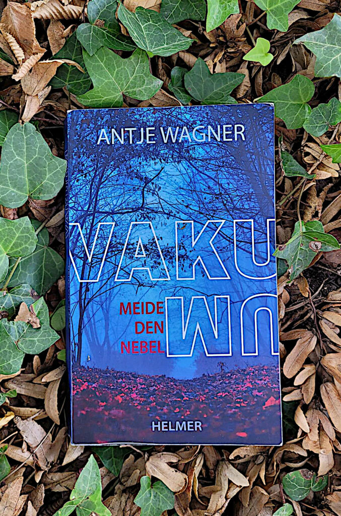 Der Jugendroman „Vakuum: Meide den Nebel“ von Antje Wagner im herbstlichen Efeulaub liegend.