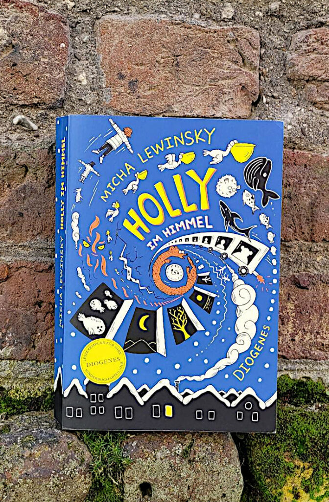 Das Kinderbuch „Holly im Himmel“ von Micha Lewinsky vor einer alten Backsteinmauer