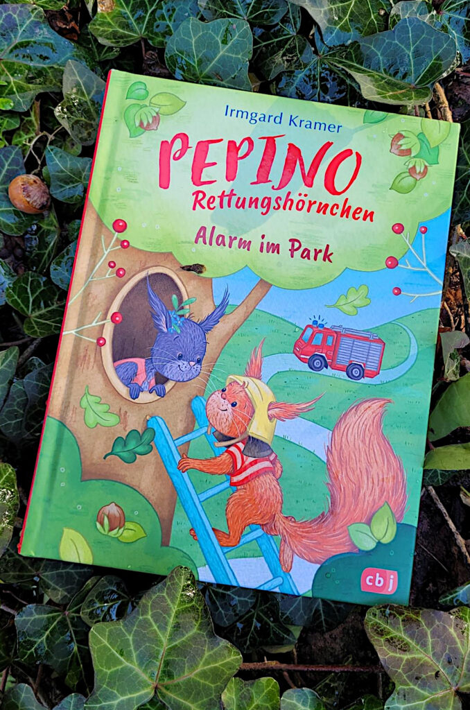 Das Kinderbuch „Pepino Rettungshörnchen: Alarm im Park“ von Irmgard Kramer und Nora Paehl in Efeu liegend