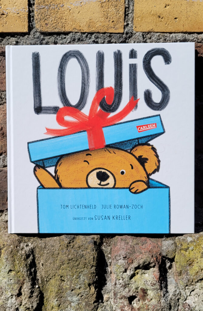 Das Bilderbuch „Louis“ von Tom Lichtenheld und Julie Rowan-Zoch vor einer alten Backsteinmauer
