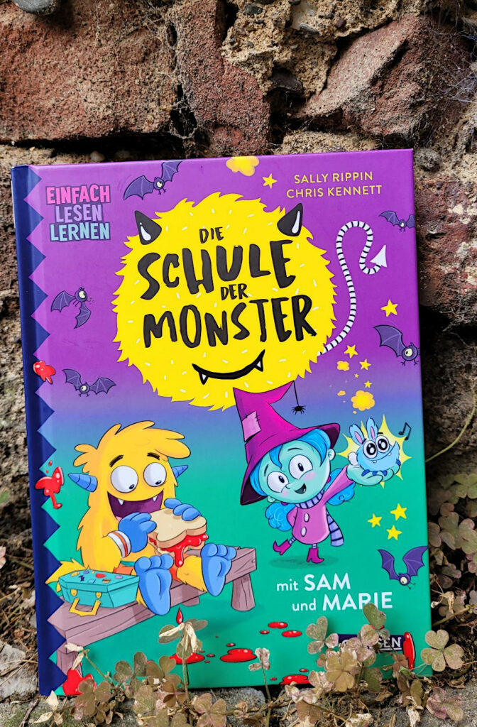 Das Kinderbuch „Die Schule der Monster mit Sam und Marie“ von Sally Rippin und Chris Kennett vor einer alten Backsteinmauer