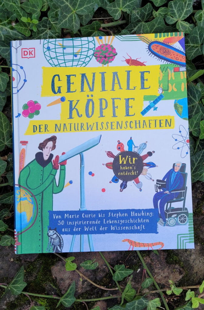 Das Sachbuch für Kinder „Geniale Köpfe der Naturwissenschaften“ von Isabel Thomas und Jessamy Hawke auf einer roten Backsteinmauer mit Efeu liegend