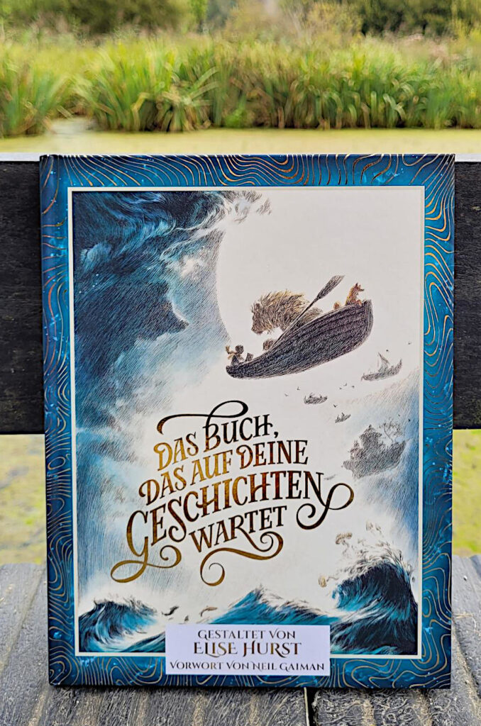 „Das Buch, das auf deine Geschichten wartet“ von Elise Hurst steht auf einer Brücke vor einem mit Entengrütze überzogen Weiher